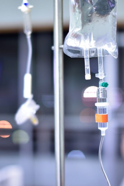 Selective focus Infusion bottle with IV solution in the patient room with blurred background woman patient on hospital bed.