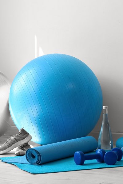 Different sports equipment on floor near white wall